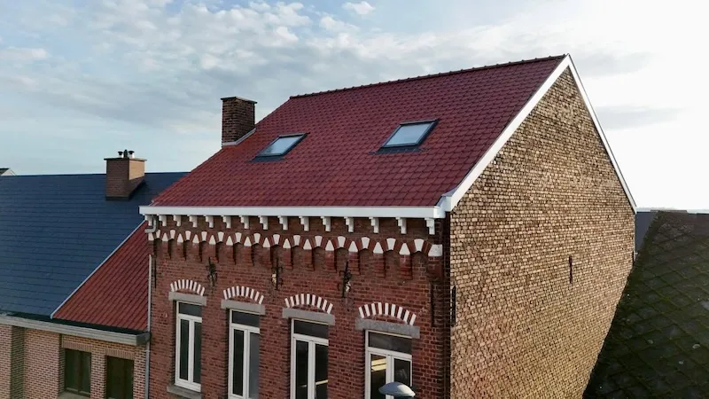 Afgewerkt hellend dak in rode pannen op een bakstenen woning